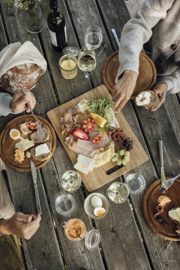 Ein Tisch mit Brot, Wurst, Käse, Gemüse und Getränken für ein Picknick.