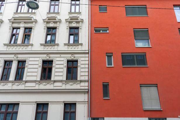 Neben einem Gründerzeitbaue: Eine glatte Fassade mit unterschiedlich angeordneten Fenstern