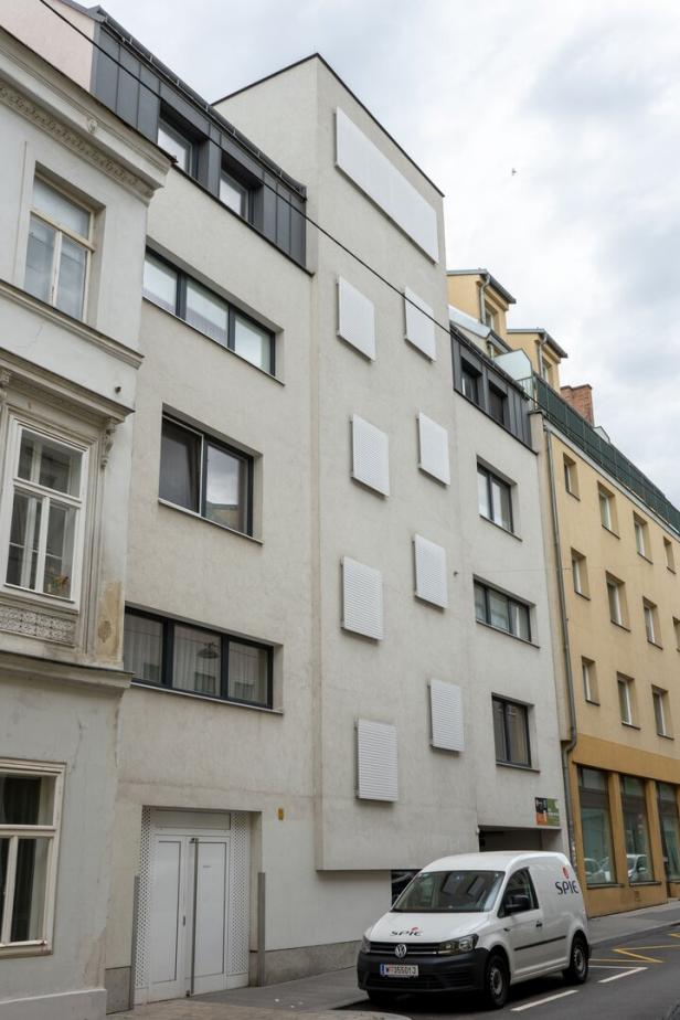 Quadratische Fenster, glatte Fassaden neben einem Gründerzeitbau