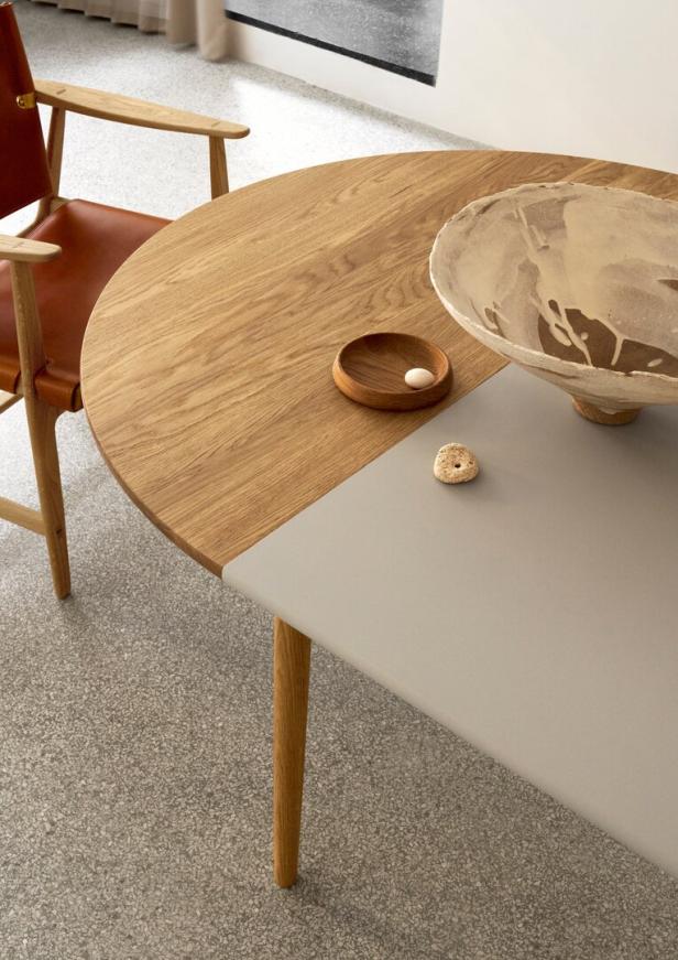 Ein runder Tisch aus Holz und grauem Material mit einer Schale und einem kleinen Teller darauf.
