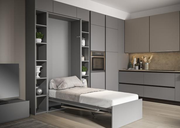 Ein ausklappbares Bett in einem modernen Apartment mit grauen Möbeln.