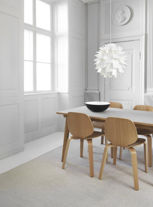 Ein Esstisch mit vier Holzstühlen in einem hellen, minimalistischen Raum.