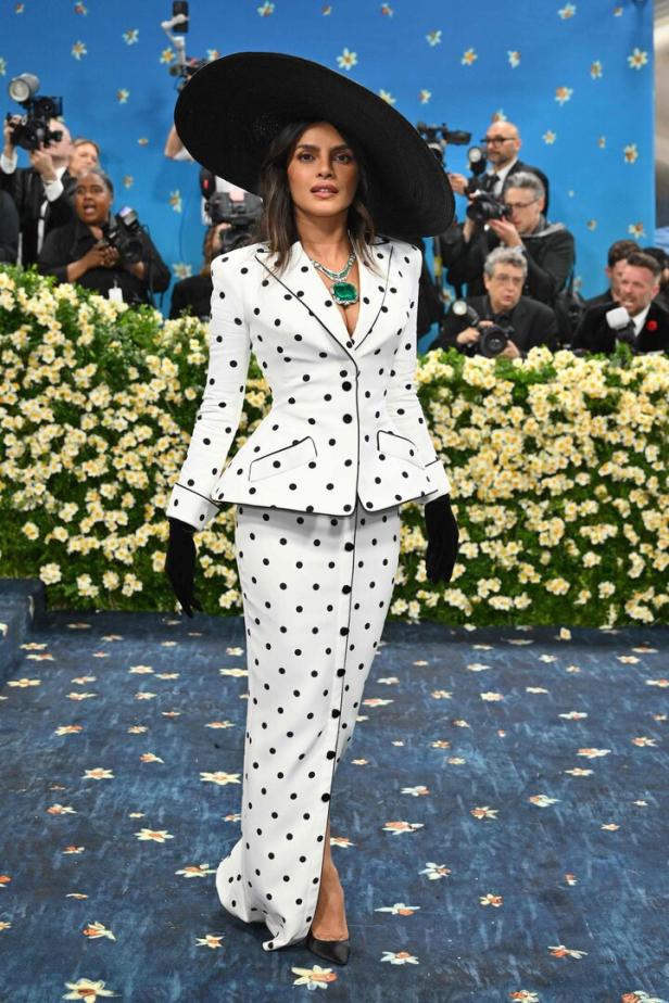 Priyanka Chopra in einem gepunkteten Anzug und einem großen Hut auf dem roten Teppich.