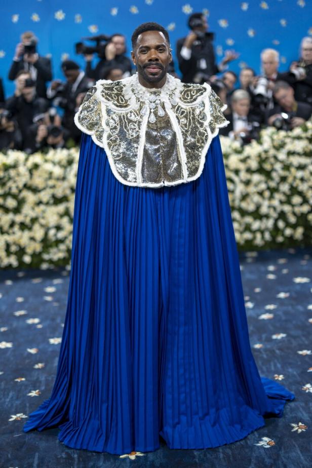 Ein Mann in einem blauen Umhang und einer verzierten goldenen Jacke auf dem roten Teppich der Met Gala 2025 im Metropolitan Museum of Art in New York.