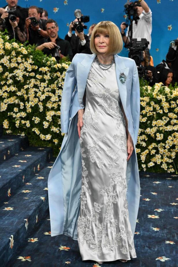 Anna Wintour auf dem roten Teppich der Met Gala in einem silbernen Kleid und hellblauen Mantel.