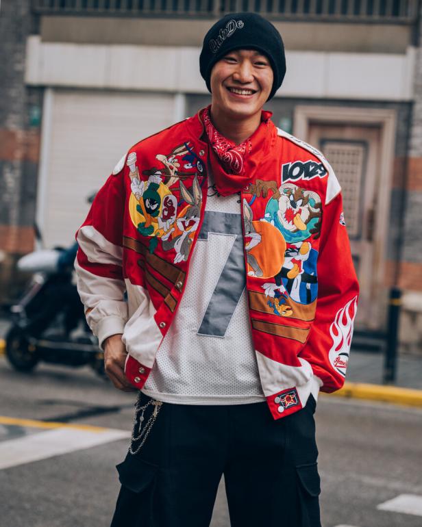 Ein lächelnder Mann in Shanghai mit einer Jacke mit Looney Tunes-Motiven.