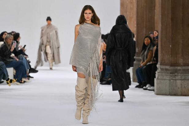 Eine Frau präsentiert ein gestreiftes Kleid und hohe Stiefel auf einer Modenschau von Sportmax in Italien.