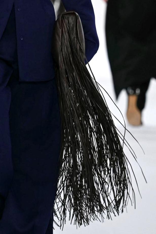 Eine braune Fransenhandtasche wird von einem Model auf dem Laufsteg getragen.