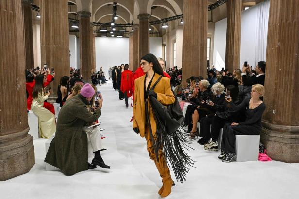 Eine Frau in einem ockerfarbenen Blazer mit Fransen läuft über einen Laufsteg bei einer Sportmax-Modenschau in Italien.