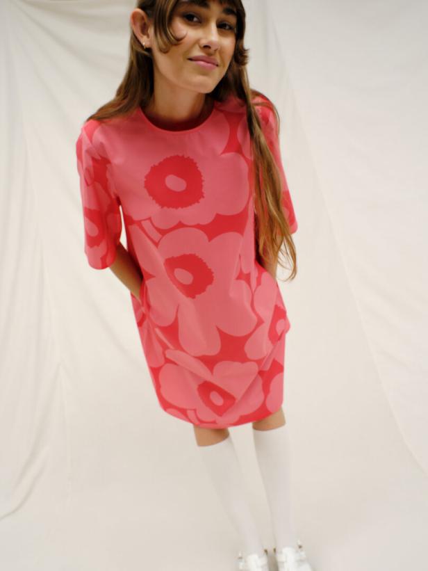 Eine junge Frau trägt ein rosafarbenes Kleid mit einem großen Blumenmuster.