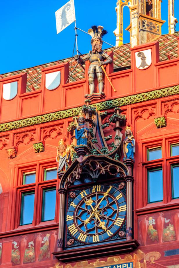 Nahaufnahme des roten Rathauses mit Uhr, Malereien und Ornamenten in Basel, Schweiz.