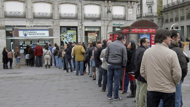 Eine lange Schlange von Menschen wartet vor einem Kiosk der staatlichen Lotterie in Madrid.