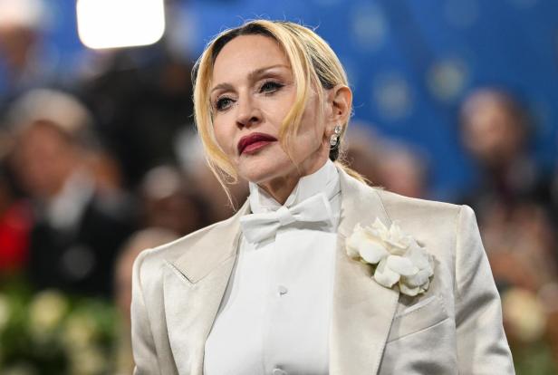 Madonna in einem weißen Hosenanzug mit Fliege und Blume.