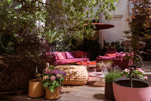 Einladende Terrasse mit roten Sofas, Tischen und üppiger Bepflanzung.