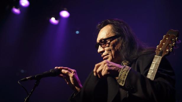 Rodriguez tritt in einem dunklen Saal mit lila Scheinwerfern auf.