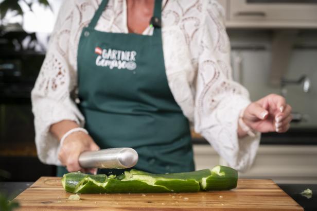 Frau zerdrückt mit Nudelholz Gurke