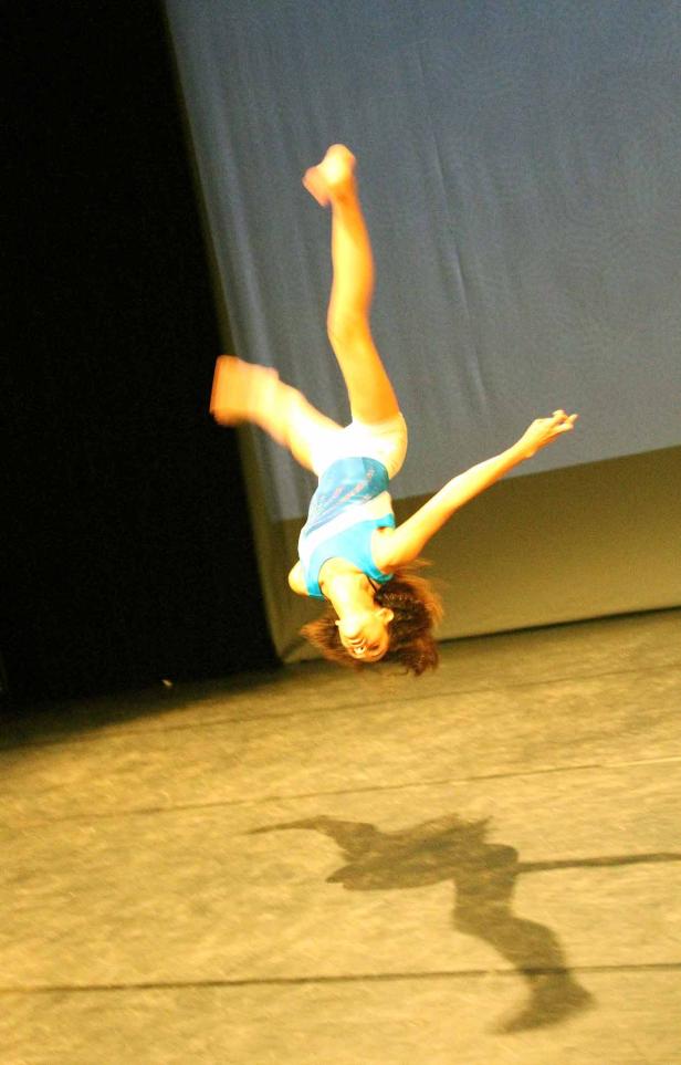 Eine Tänzerin macht einen Flickflack auf einer Bühne.