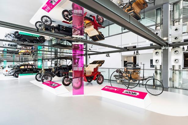 Museumsausstellung mit historischen Autos und Motorrädern, darunter der Benz Patent-Motorwagen und das Ford T-Modell.