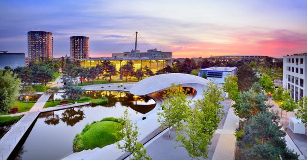 Stadtansicht mit Fluss und Brücke bei Sonnenuntergang, gelegen zwischen Wolfsburg und Volkswagenwerk.
