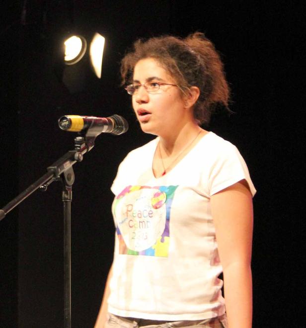 Eine junge Frau spricht bei einer Veranstaltung ins Mikrofon.