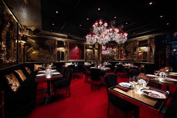 Ein luxuriöses Restaurant mit rotem Teppich und dunkler, goldverzierter Einrichtung.