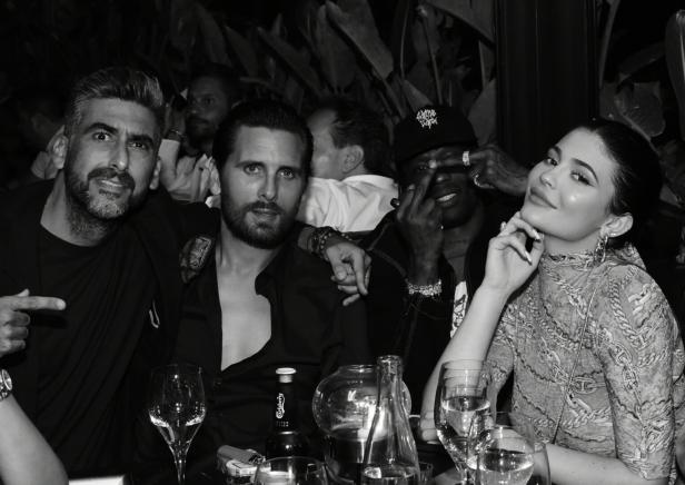 Eine Gruppe von Personen, darunter Kylie Jenner und Scott Disick, sitzen an einem Tisch in einem Restaurant.