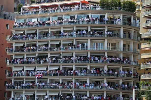 Viele Menschen beobachten ein Ereignis von den Balkonen eines mehrstöckigen Gebäudes aus.