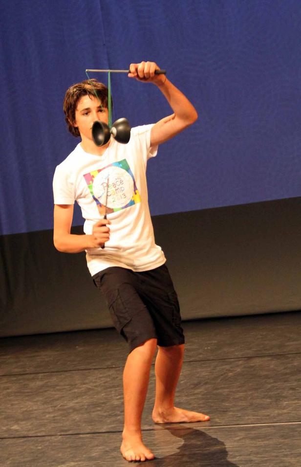 Ein barfüßiger Junge führt auf einer Bühne ein Diabolo-Kunststück vor.