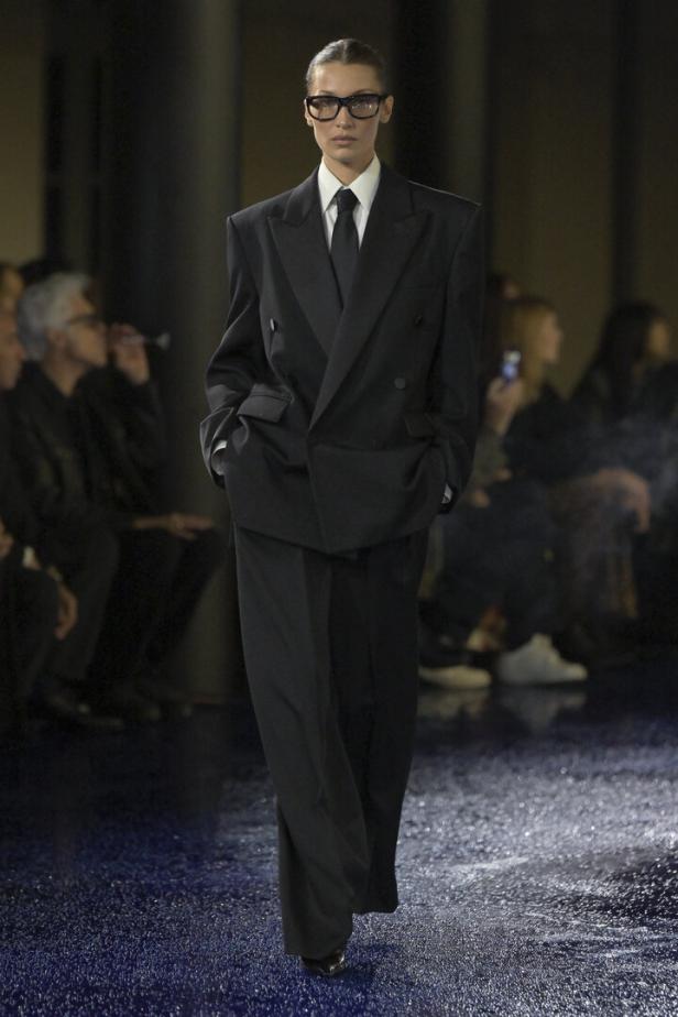 Ein Model in einem übergroßen schwarzen Anzug auf dem Laufsteg der Saint Laurent Show.