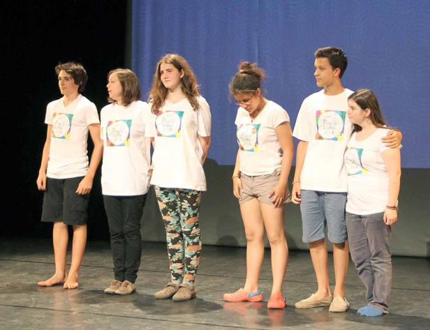 Eine Gruppe Jugendlicher steht auf einer Bühne und trägt T-Shirts mit der Aufschrift „Peace Camp 2013“.