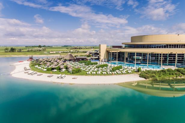 Ein Resort mit Strand, Liegestühlen und einem großen Gebäude am Ufer eines Sees.