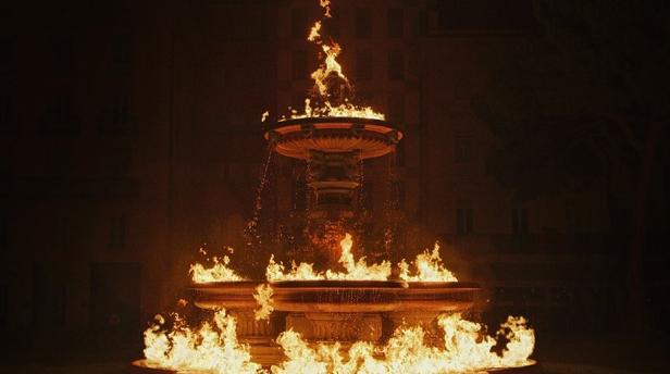 Ein Brunnen mit lodernden Flammen, der in der Nacht leuchtet.