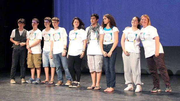 Eine Gruppe Jugendlicher steht auf einer Bühne und trägt T-Shirts mit der Aufschrift „Peace Camp 2013“.
