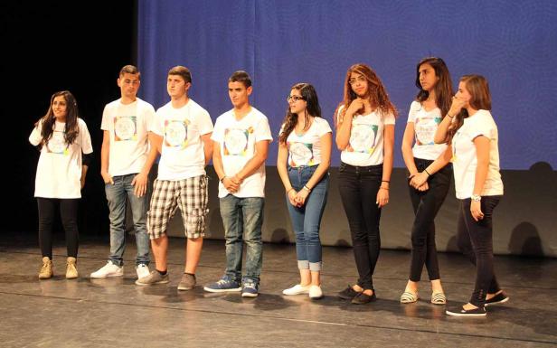 Eine Gruppe junger Leute steht auf einer Bühne und trägt T-Shirts mit der Aufschrift „Peace Camp“.