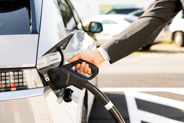 Ein Mann im Anzug lädt sein E-Auto an einer Ladestation von Wien Energie auf.