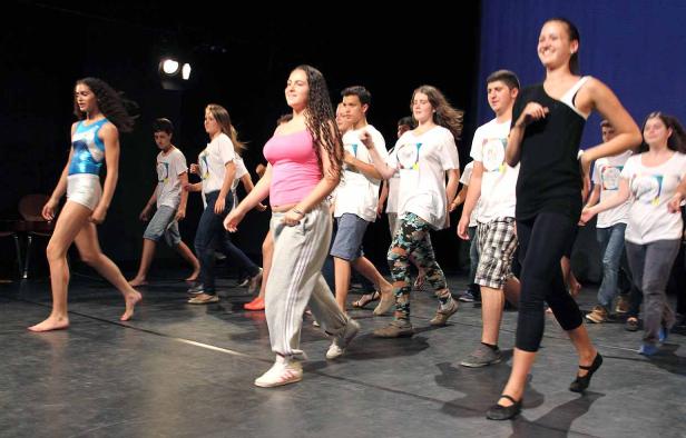 Eine Gruppe junger Leute geht barfuß oder mit Schuhen auf einer Bühne.