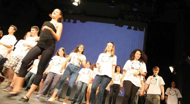 Eine Gruppe junger Leute steht auf einer Bühne und führt eine Tanzperformance auf.