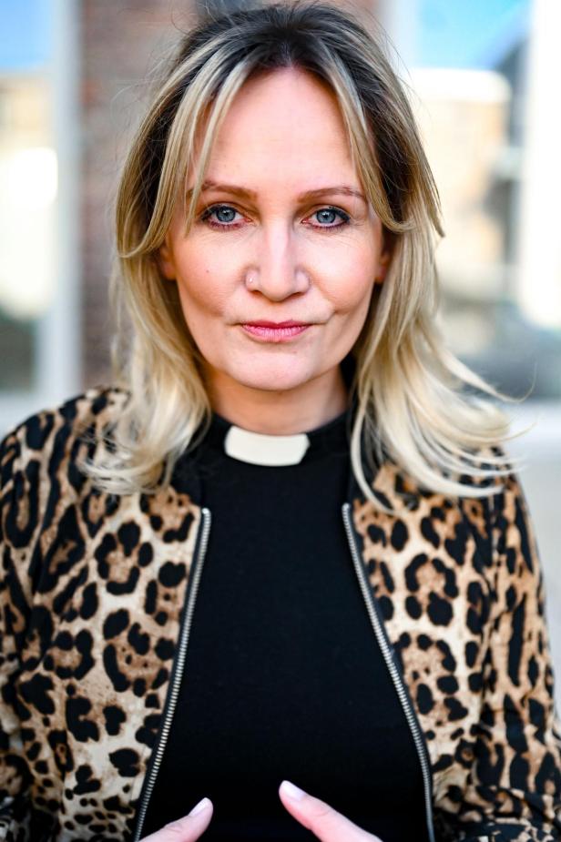 Eine Pastorin mit einer Print-Weste schaut in die Kamera. 