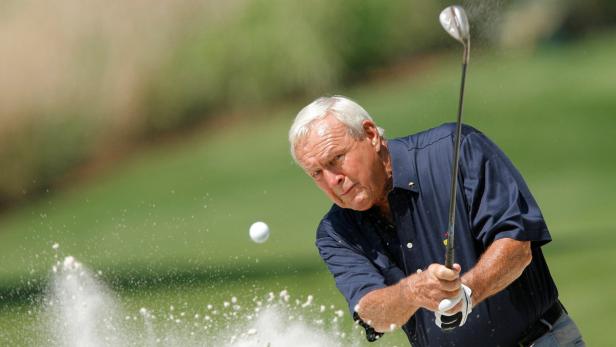 Ein älterer Mann schlägt einen Golfball aus einem Sandbunker.