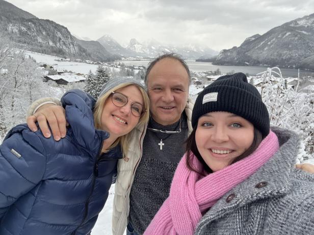 Eine Familie macht ein Selfie vor einer verschneiten Berglandschaft.