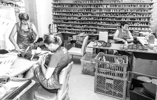 Drei Frauen arbeiten in einer Werkstatt an der Herstellung von Schuhen.