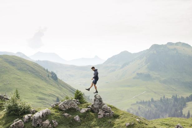 Ein Mann balanciert auf einem Felsen in den Kitzbüheler Alpen.