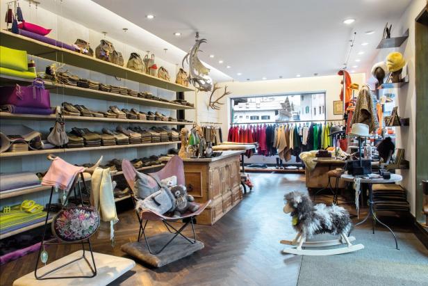 Innenansicht eines Bekleidungsgeschäfts in Kitzbühel mit Regalen, Kleidung und Dekorationen.