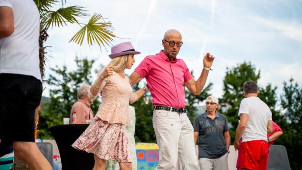 Ein Paar im bunten Sommer-Outfit tanzt zu lateinamerikanischer Musik.