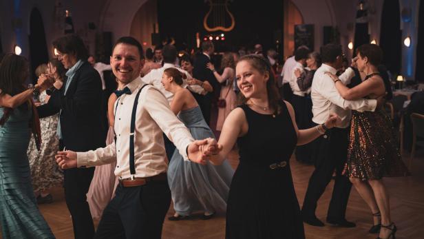 Ein Mann mit Hosenträger und Fliege tanzt mit einer elegant gekleideten Frau zu Lindy Hop.