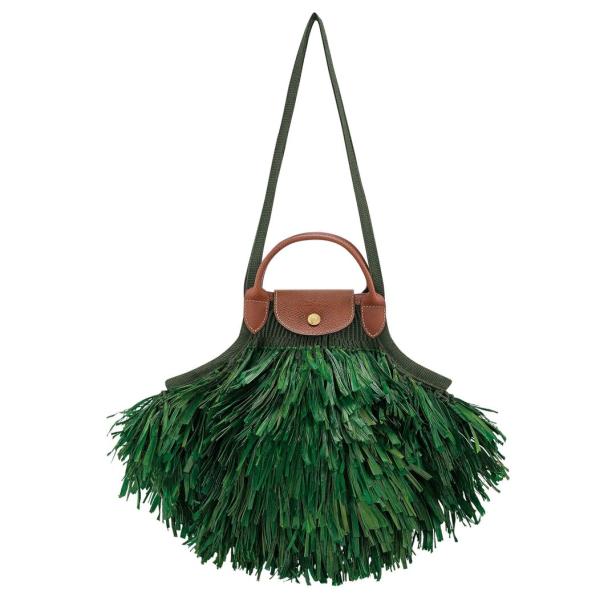 Eine grüne Handtasche mit Fransen und braunen Lederdetails hängt an einem Band.