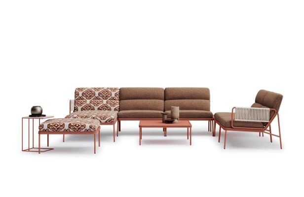 Eine Wohnzimmergarnitur mit Sofa, Sessel, Hocker und Tisch in Braun- und Orangetönen.