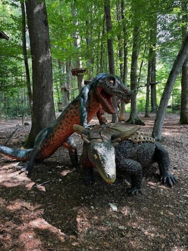 Zwei Dinosaurier-Statuen stehen im Wald.