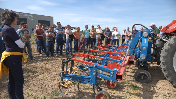 Eine Gruppe von Menschen steht um einen Traktor herum und diskutiert.