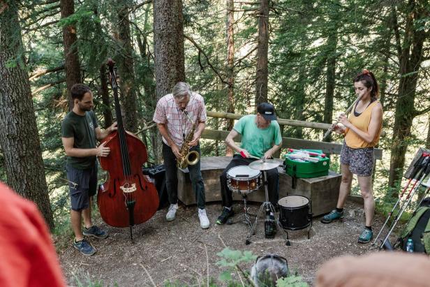 Eine vierköpfige Band spielt inmitten eines Waldes auf ihren Instrumenten.